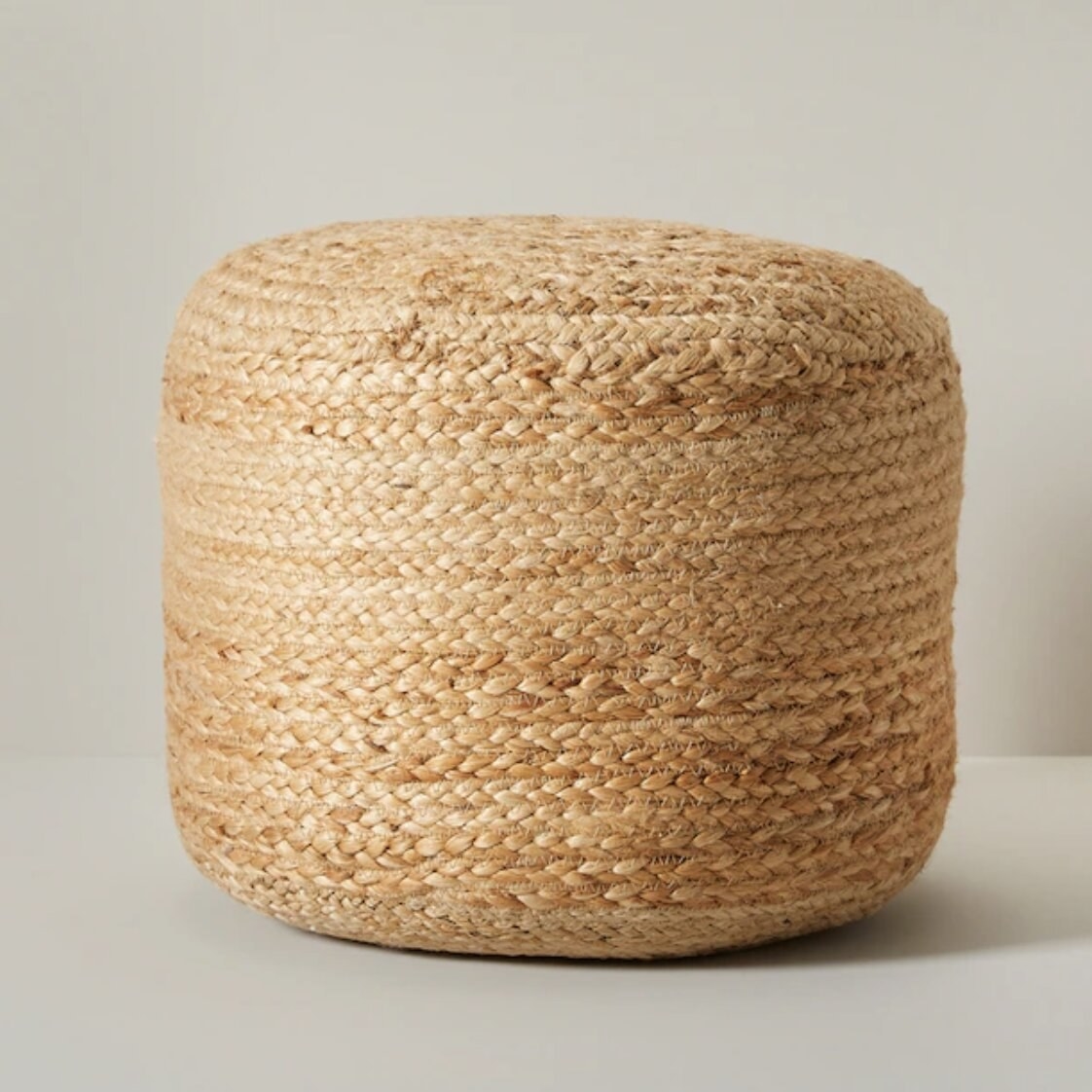 The round jute ottoman against a plain background