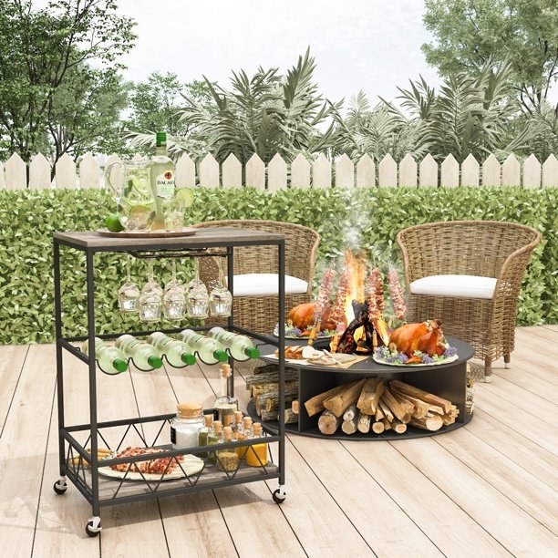 Bar cart with drinks on it next to a fire pit and chairs on a patio