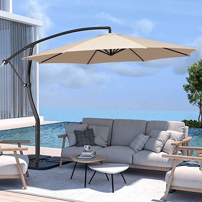 The umbrella open over a couch with a pool in the background