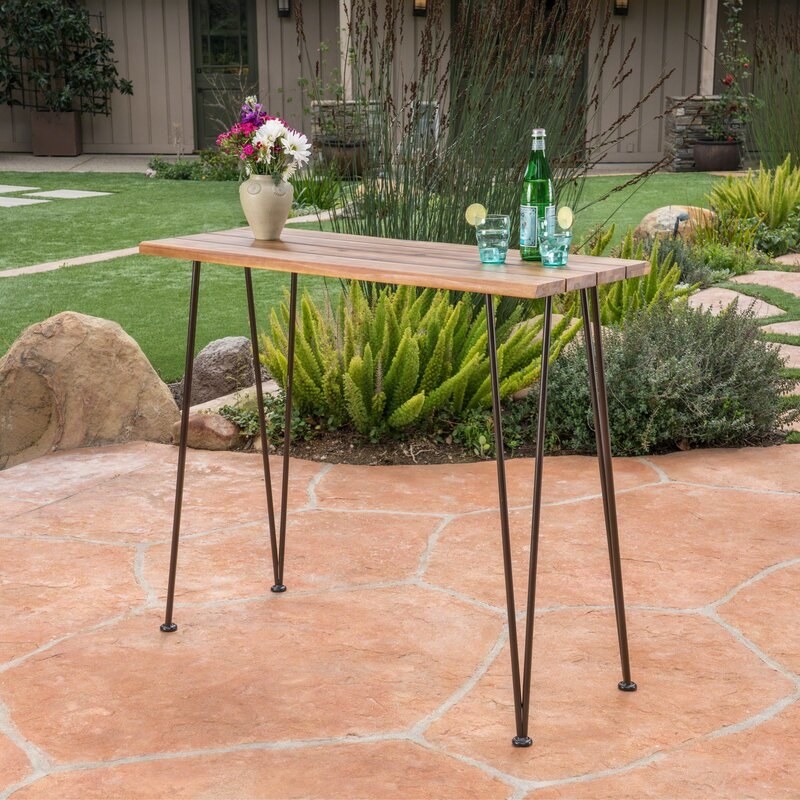 the wooden table with black hairpin legs in a yard
