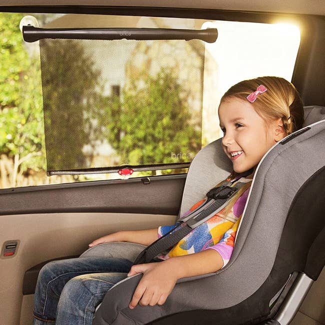 A child in a car with the window shades on