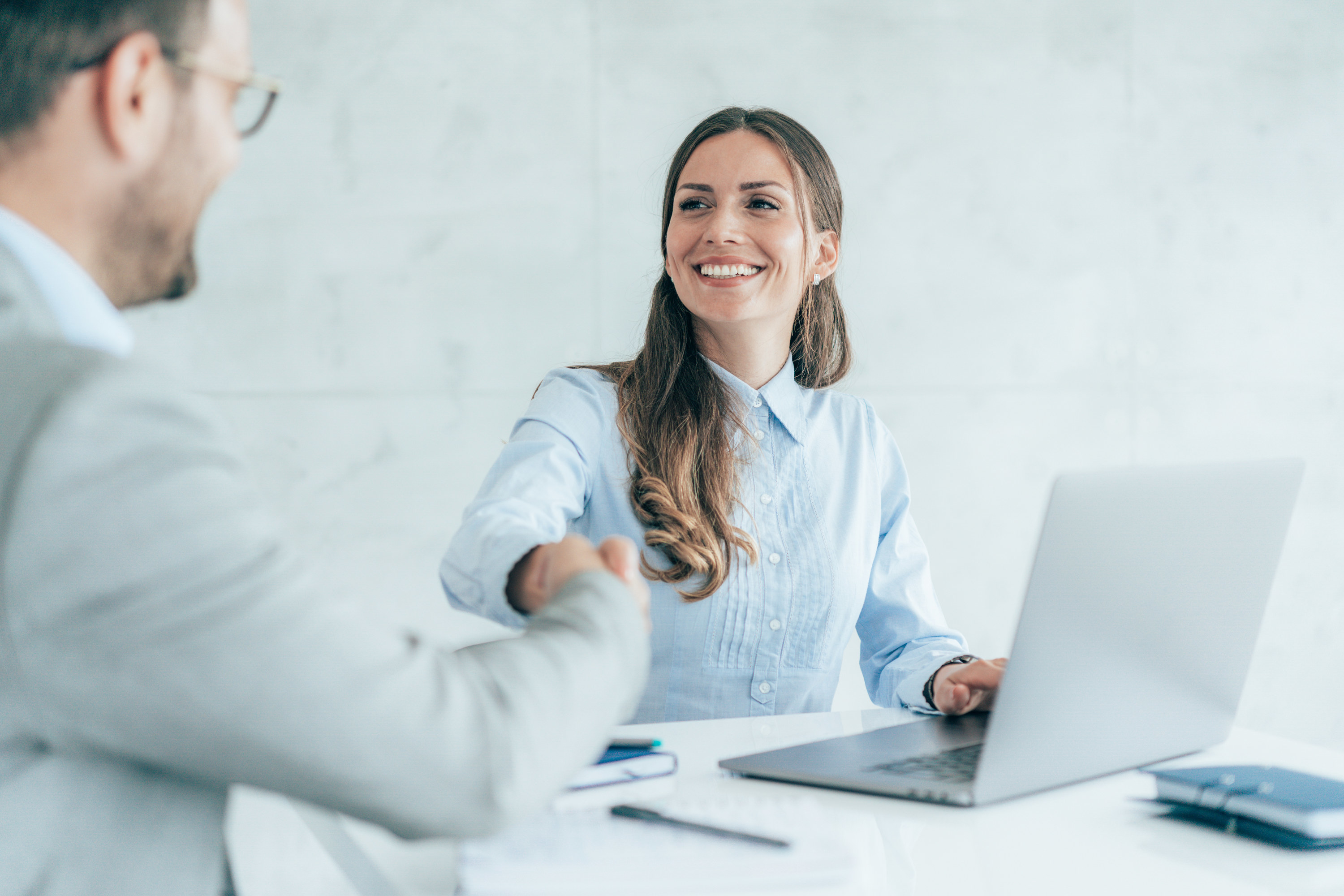 A woman smiles and shakes hands with a male business colleague