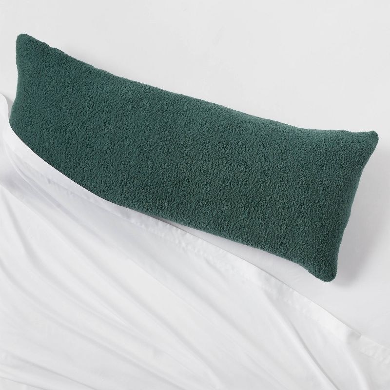 the pillow in dark green on a bed