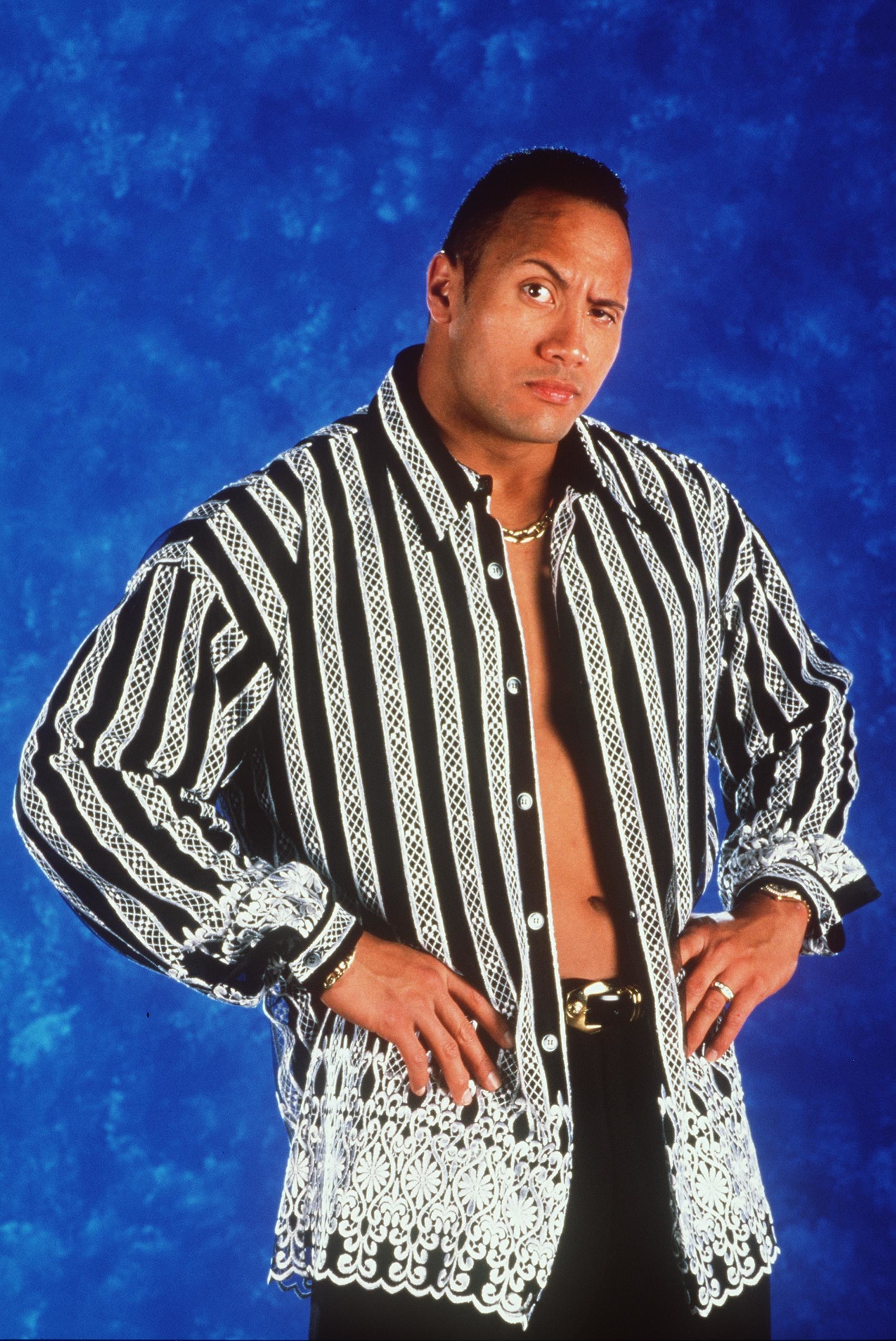 old photo of The Rock with his hands on his hips  wearing a colorful shirt