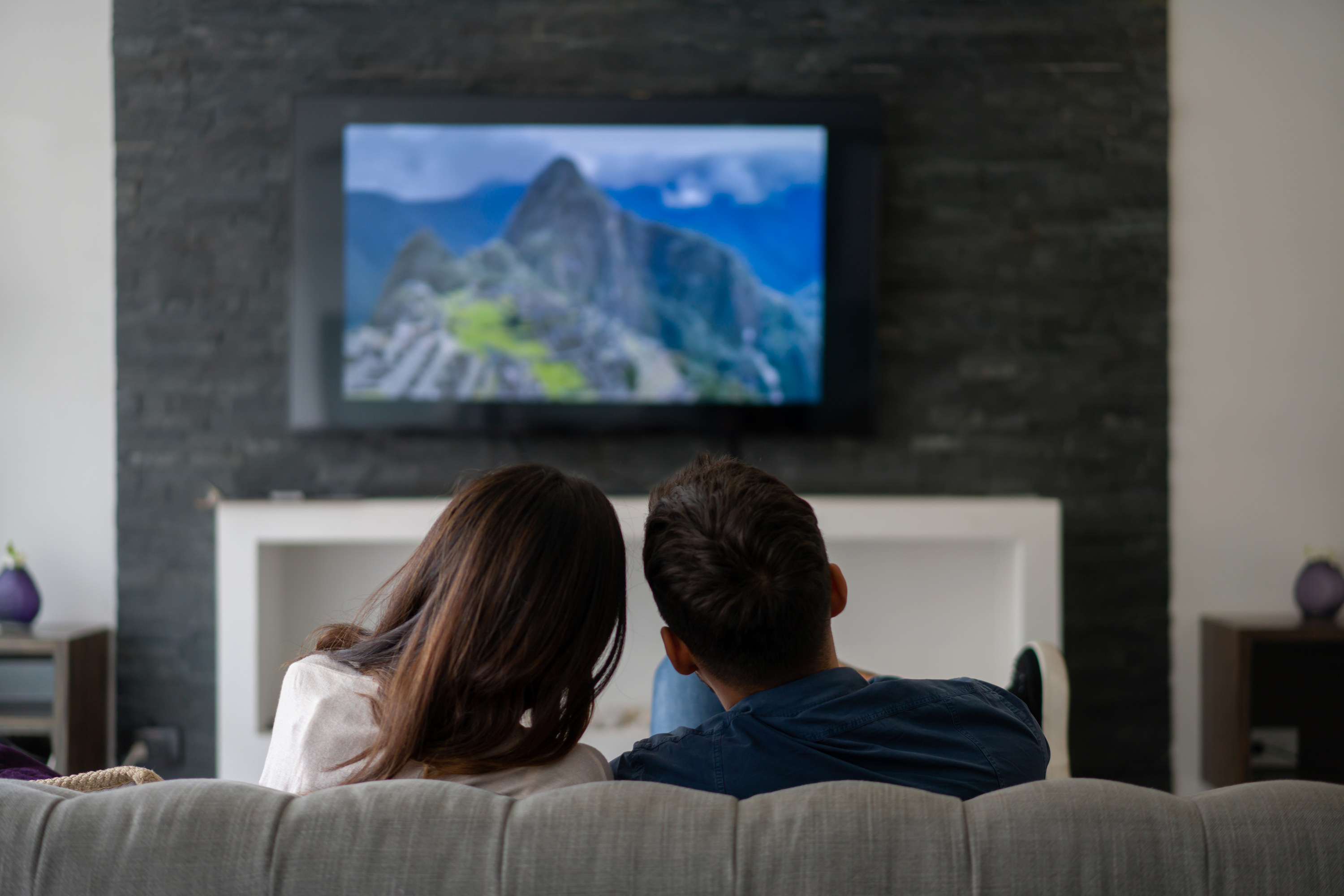 A couple sits on the couch and watches a show