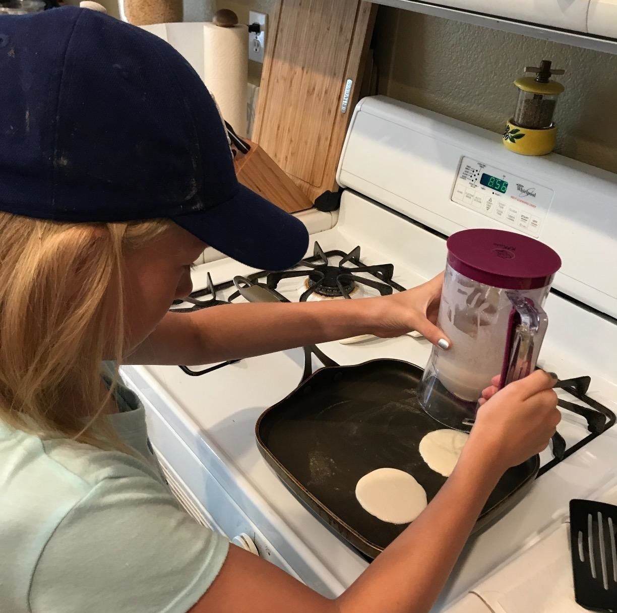 Reviewer using batter dispenser to make pancakes in skillet