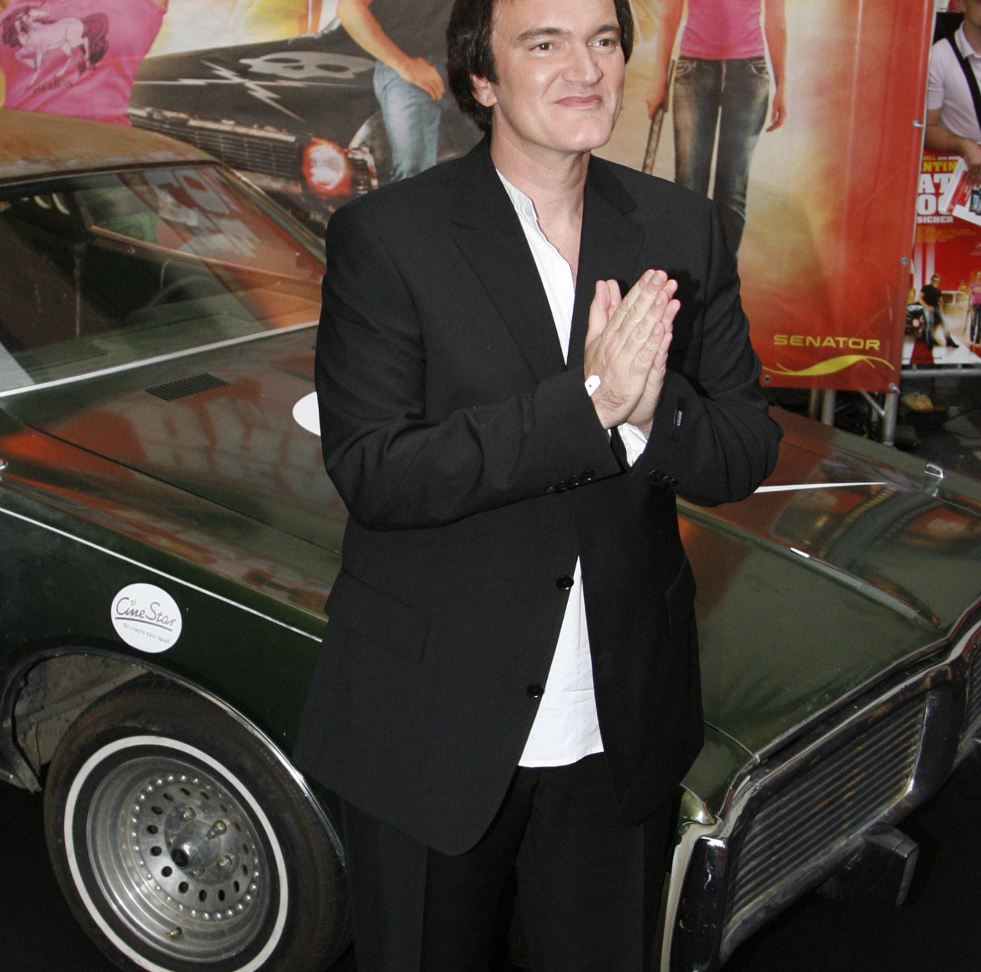 Tarantino at a Death Proof event inf ront of a car and movie poster