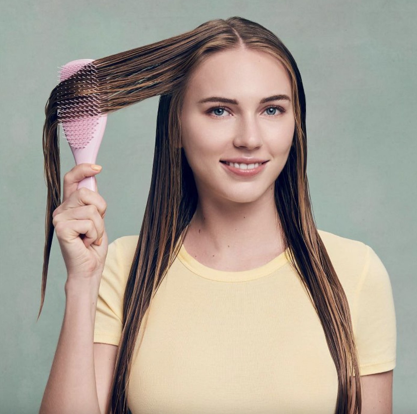 A person using a hair brush to detangle their hair