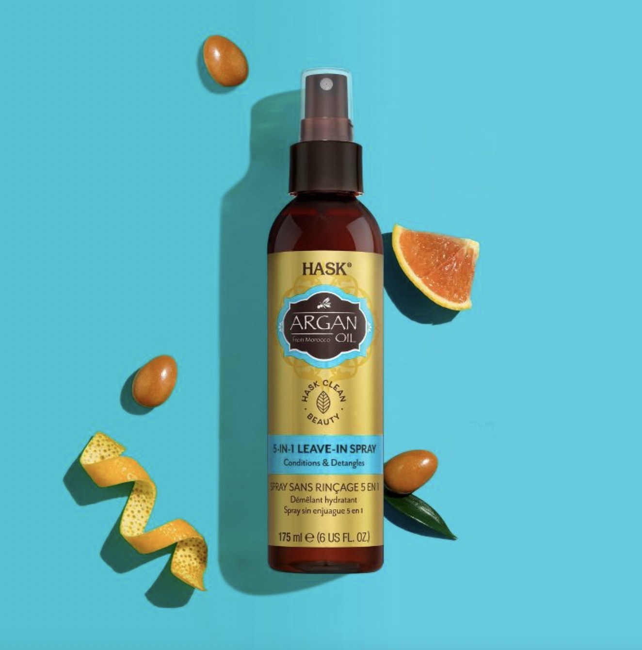 A bottle of leave-in hair spray with an orange peel, seeds and sliced citrus