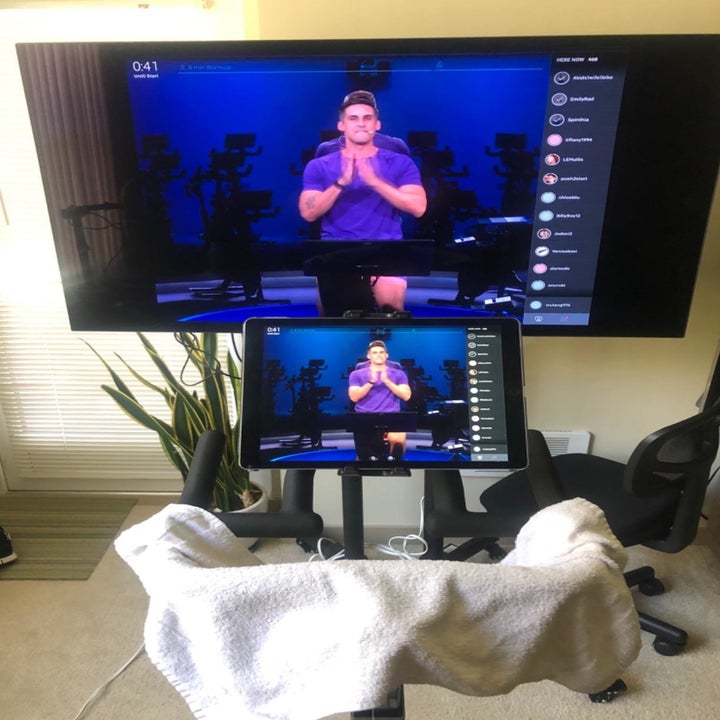 Reviewer's photo from pov of sitting on the bike with peloton workout app set up on screen and tv