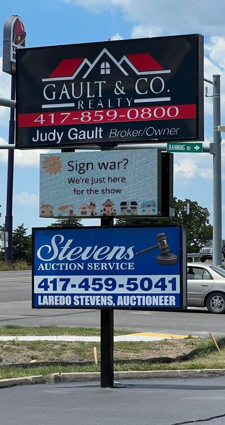 A real estate company sign says "Sign war? We're just here for the show"