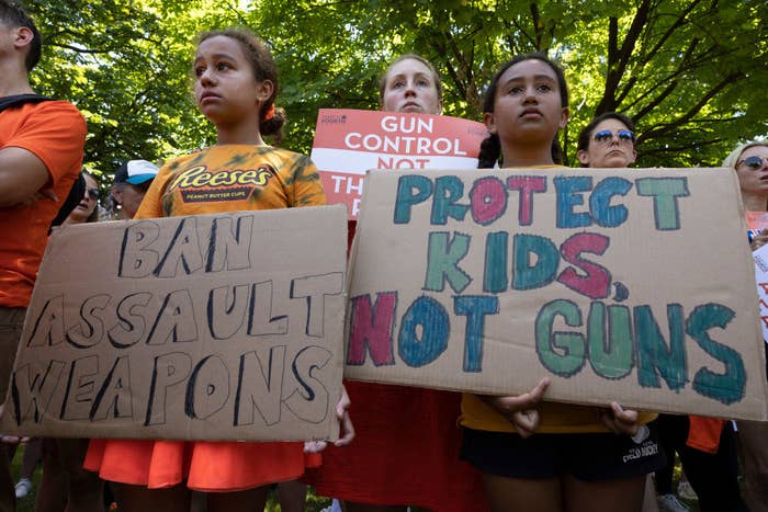 Young children at a protest holding signs that says &quot;protect kids, not guns&quot; and &quot;ban assault weapons&quot;