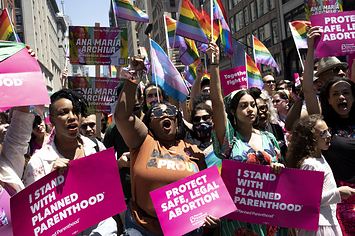 Protesters wave rainbow pride flags and hold signs that read i stand with planned parenthood