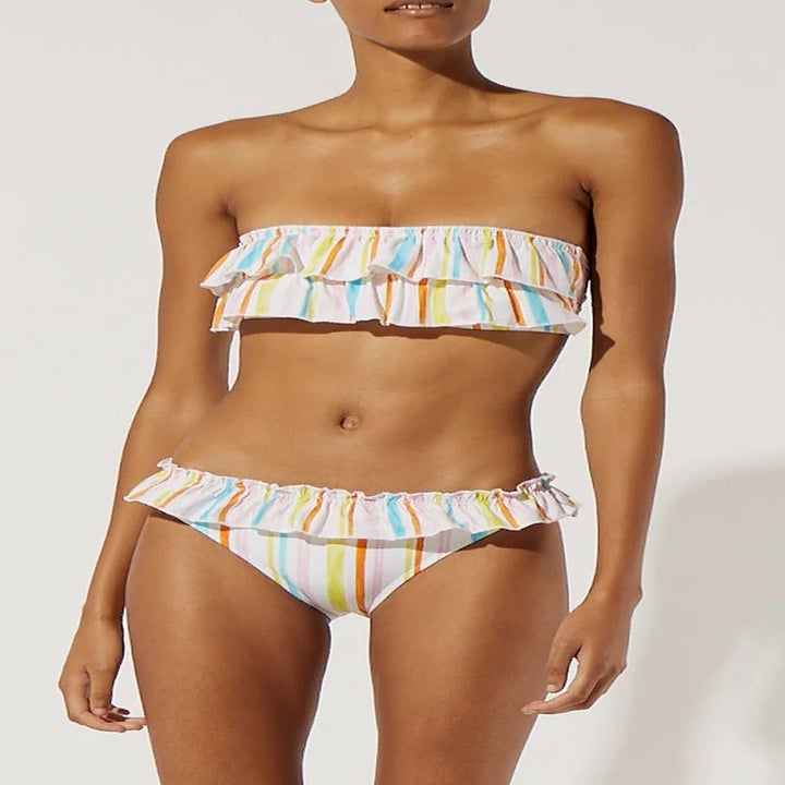 a model wearing a ruffled white and rainbow striped bandeau bikini