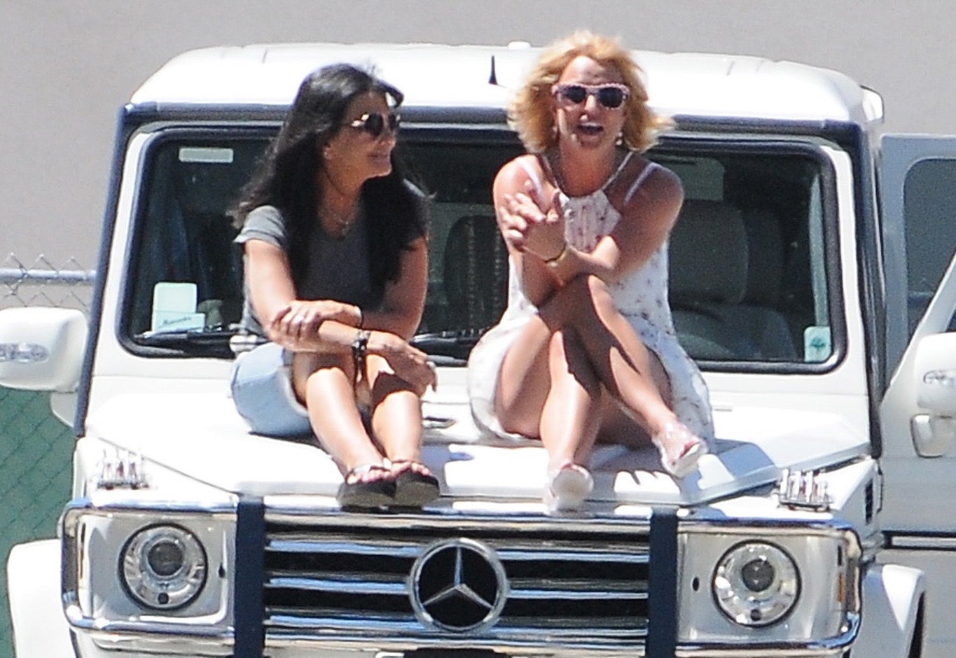 Britney sits on the hood of a car while chatting with her mom