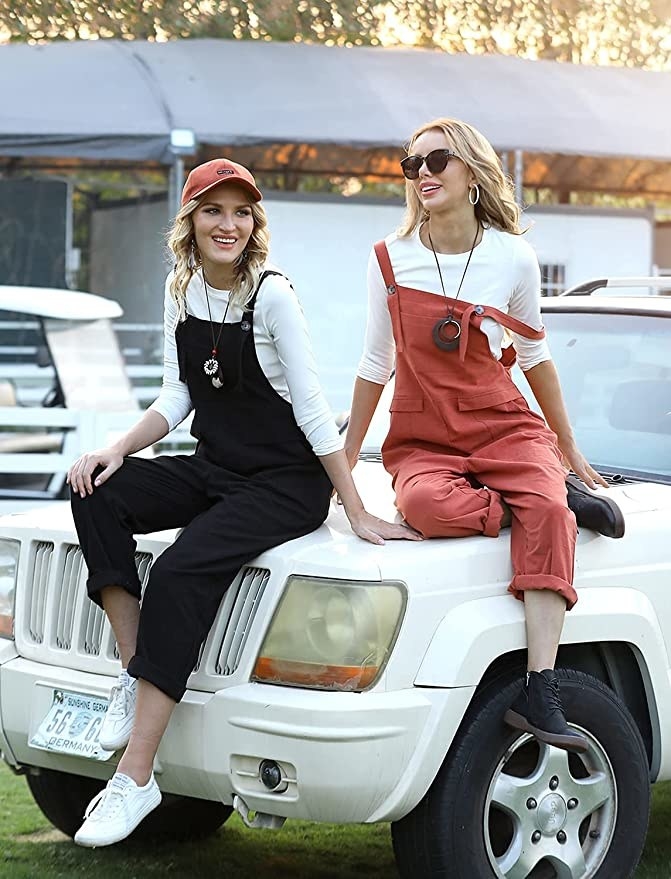 Two people wearing the overalls while sitting on a car
