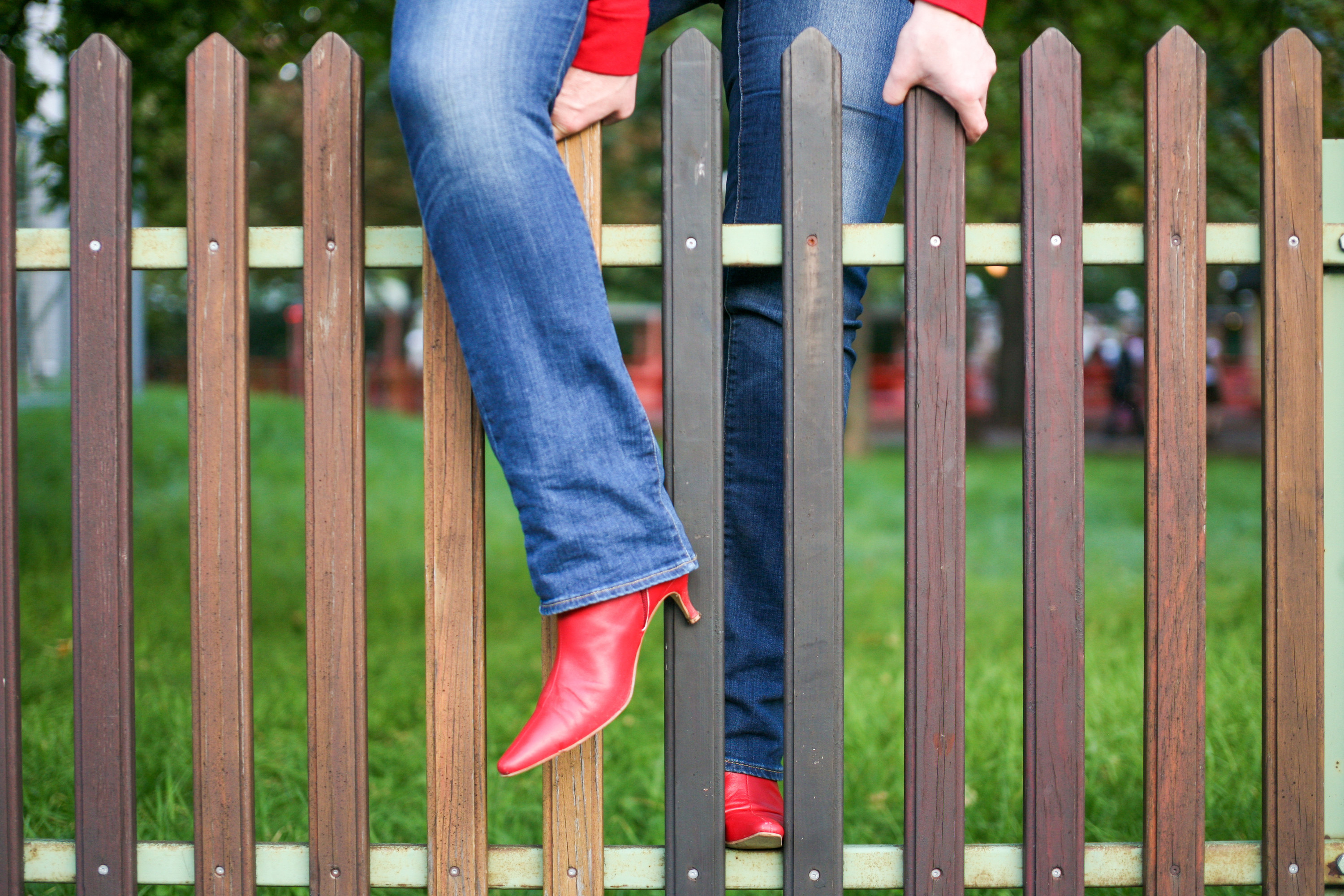 person in jeans and boots climbing a fence