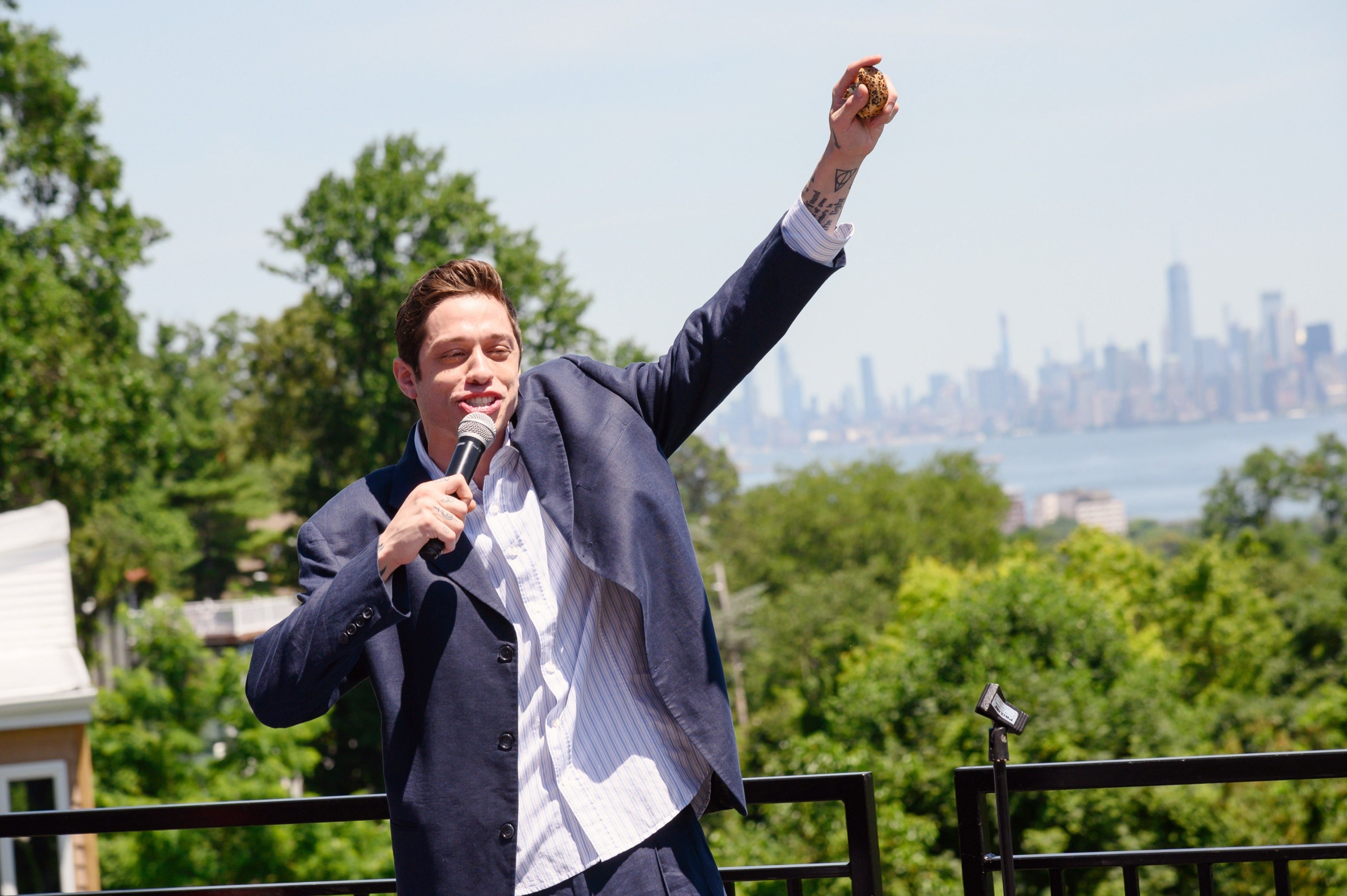 Pete standing outside speaking into a microphone with the Manhattan skyline in the background