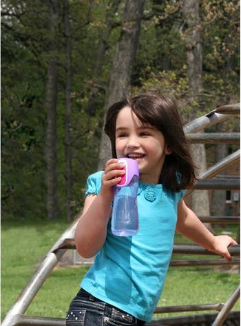 A child holding the water bottle on the playground