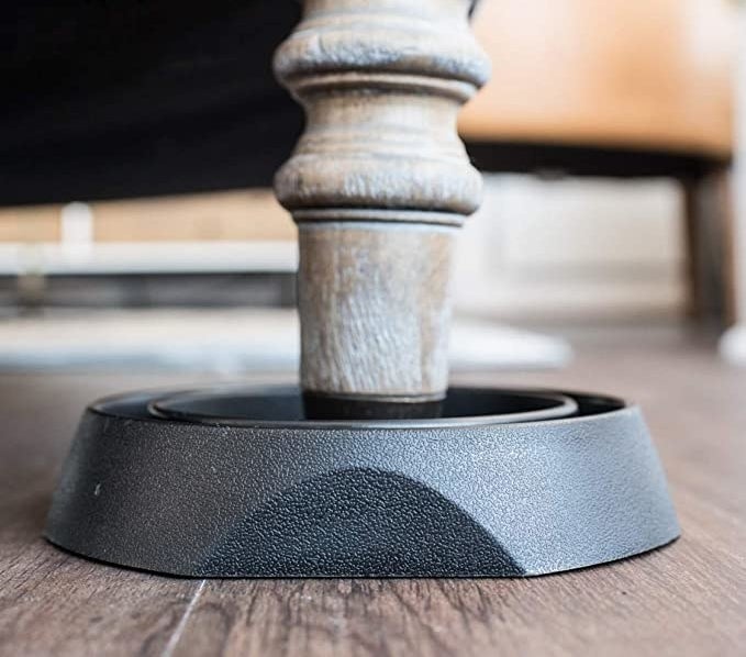 a leg of a bed sitting in the plastic dish on a hardwood floor