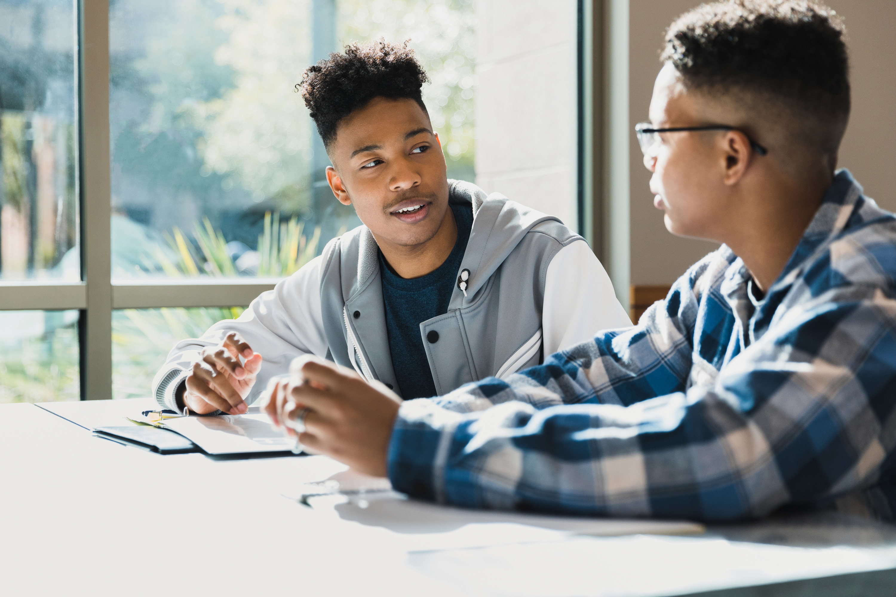 two friends talking at a desk