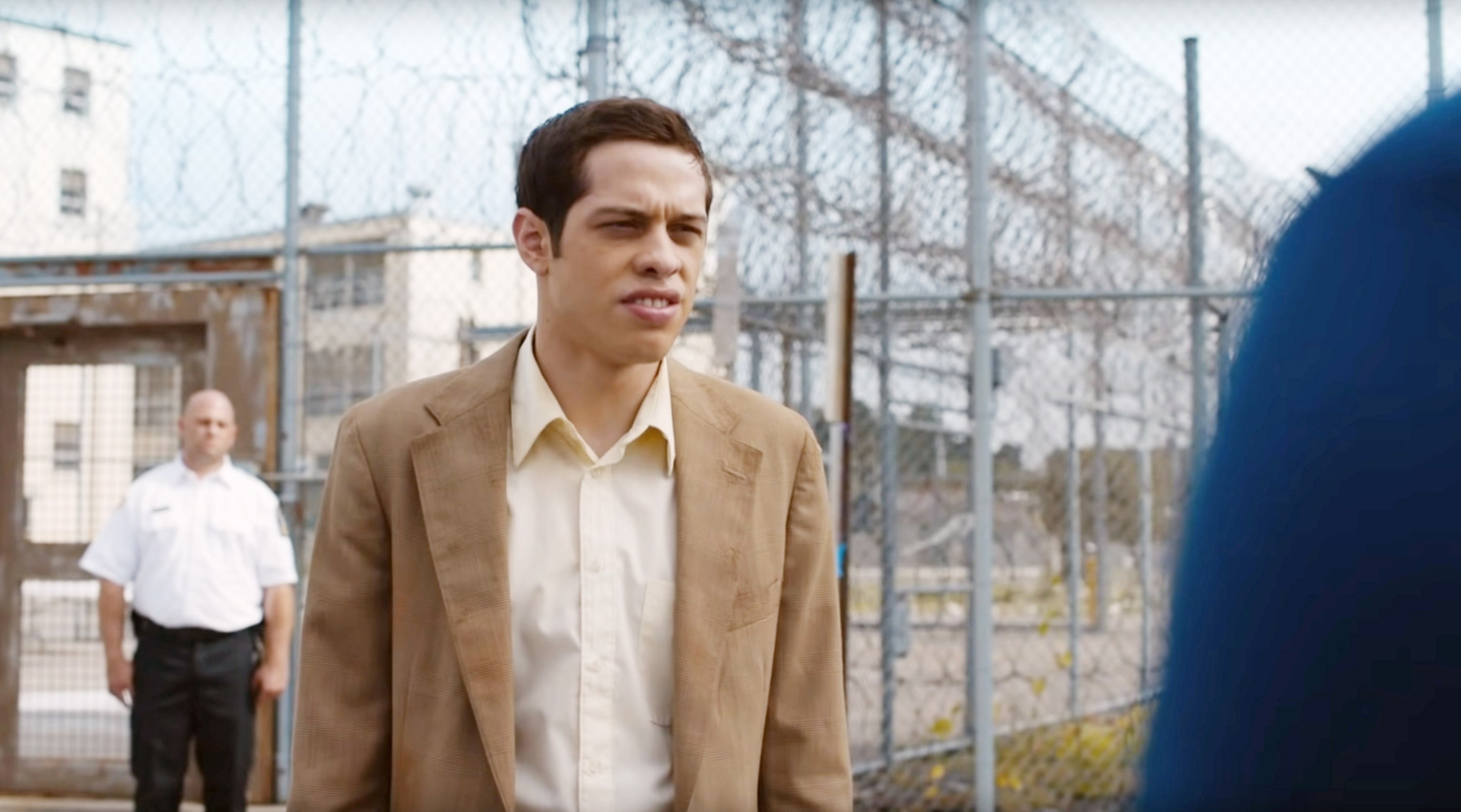Pete in a jacket and shirt and standing outside a prison