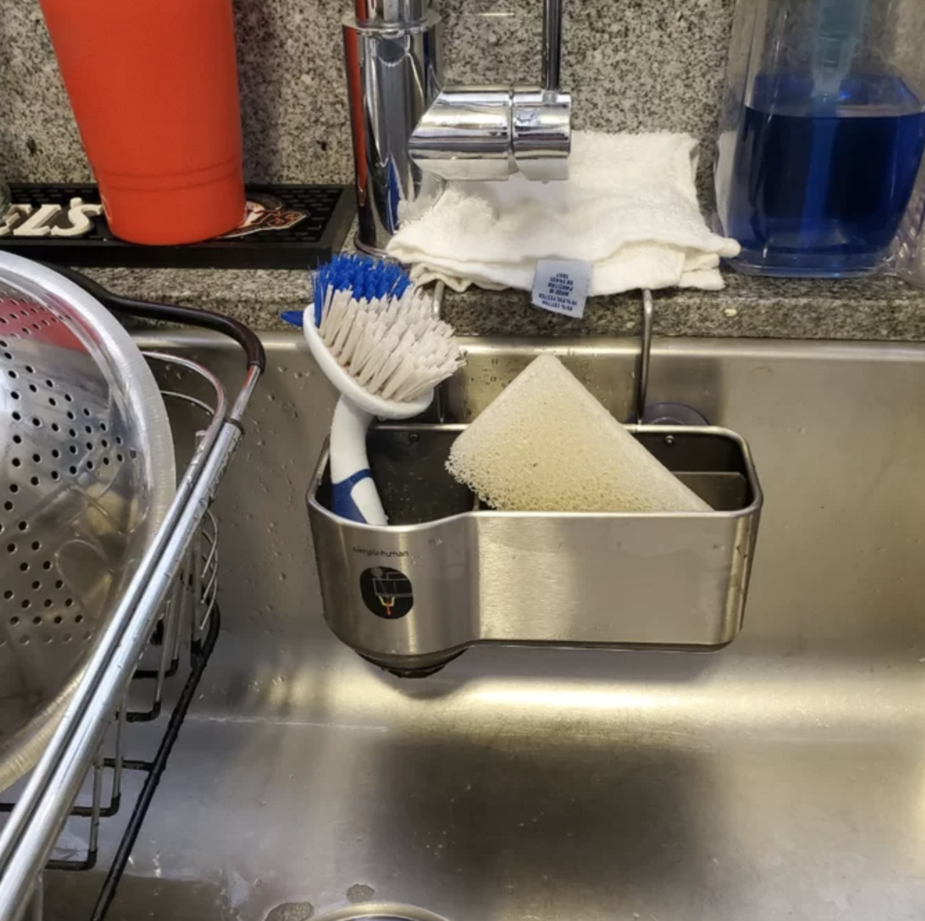 stainless steel sink caddy mounted on the inside of a sink