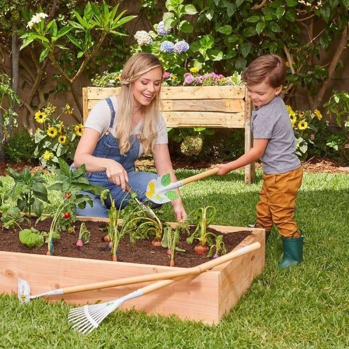 A kid and parent with garden tools