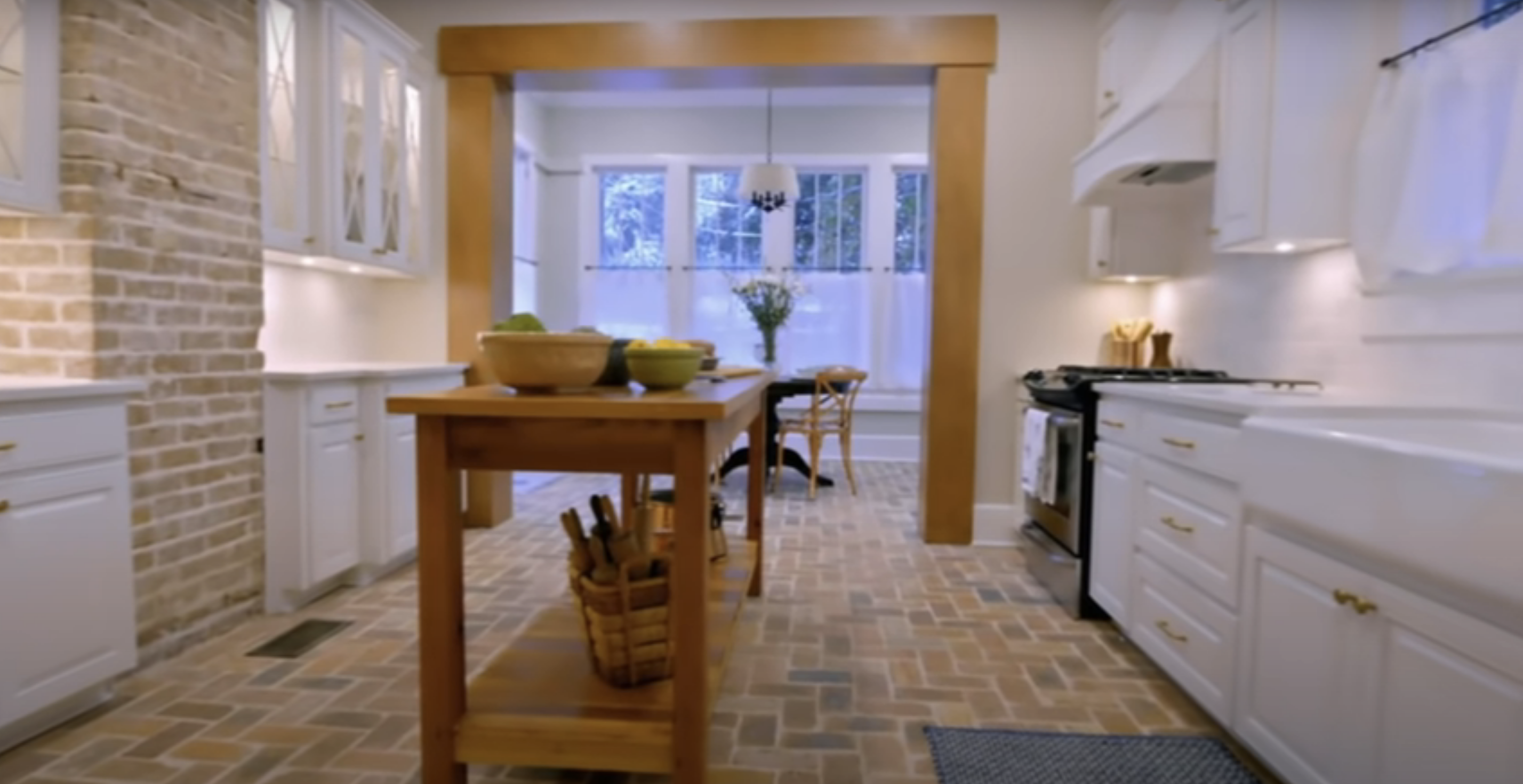 A kitchen designed by Erin and Ben, including a brick floor and a rustic wood island