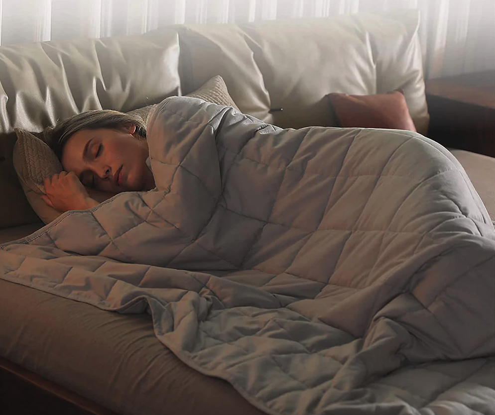 A model under a light grey quilted blanket