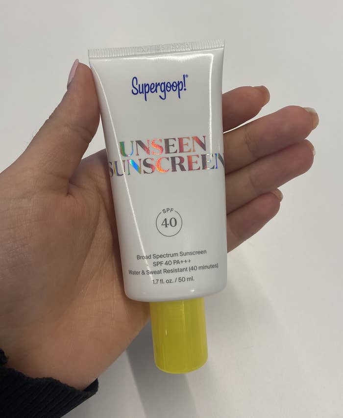 The writer holding a bottle of Unseen Sunscreen