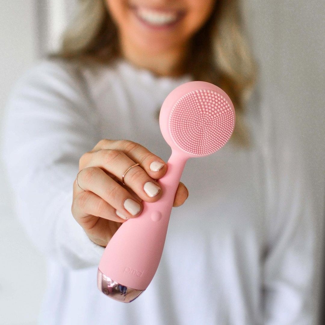 a person holding out the facial cleansing brush