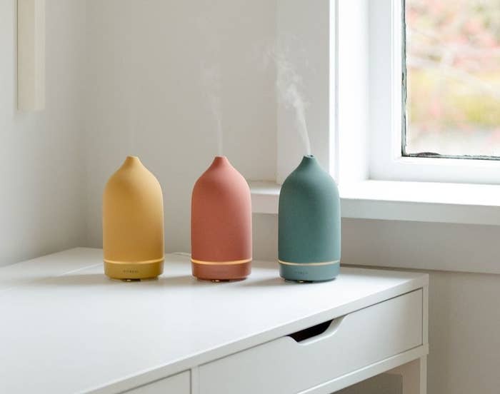 Three diffusers on, on a desk beside a window