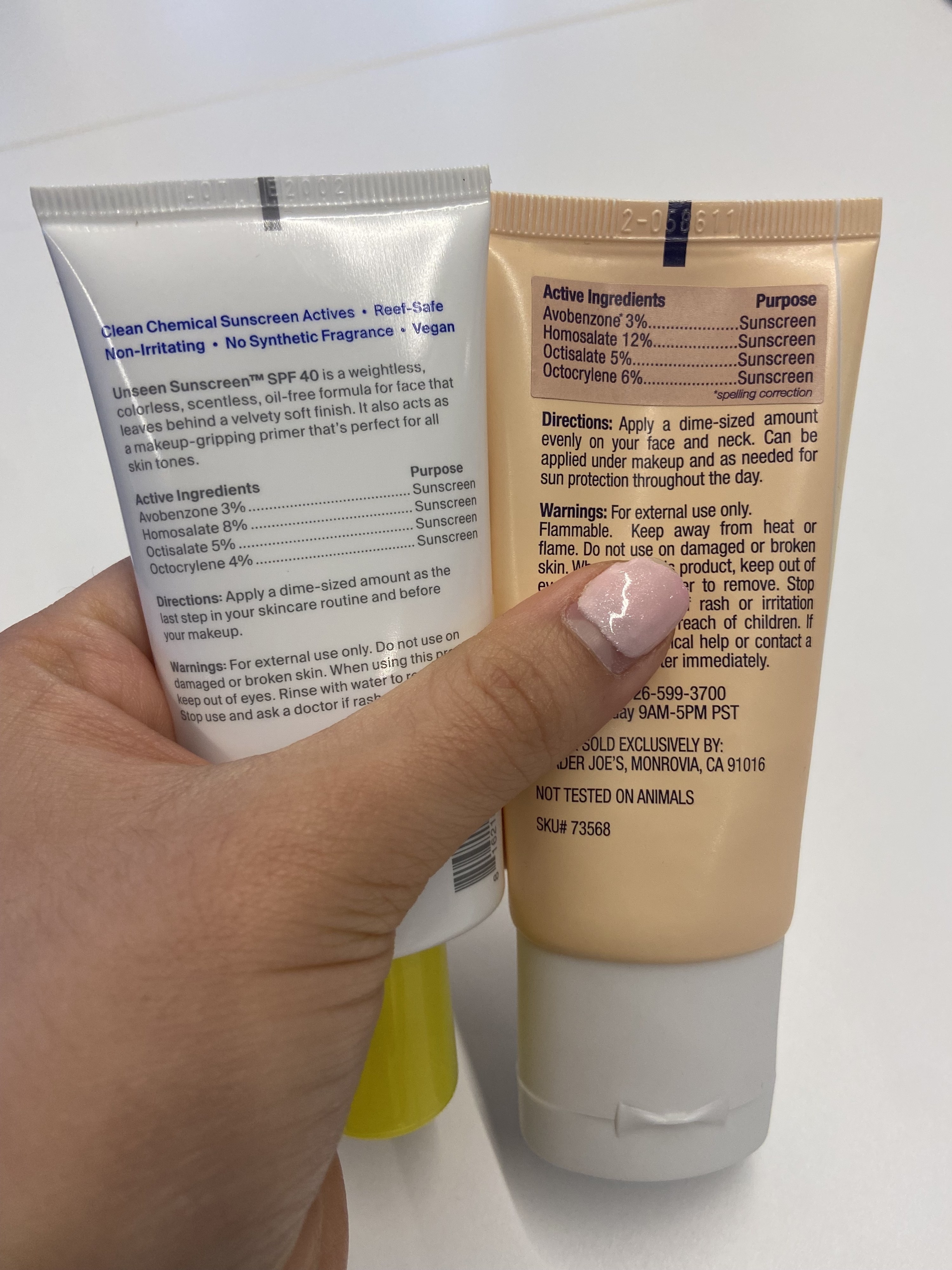 The writer holding both bottles side-by-side to show the ingredients list on the back
