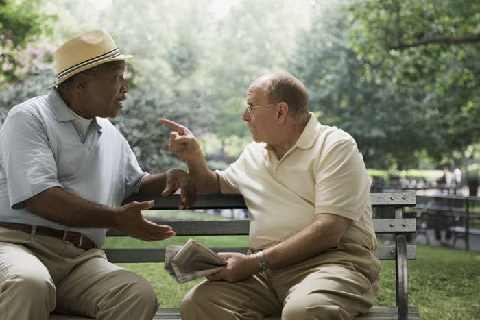 two older men arguing on a park bench
