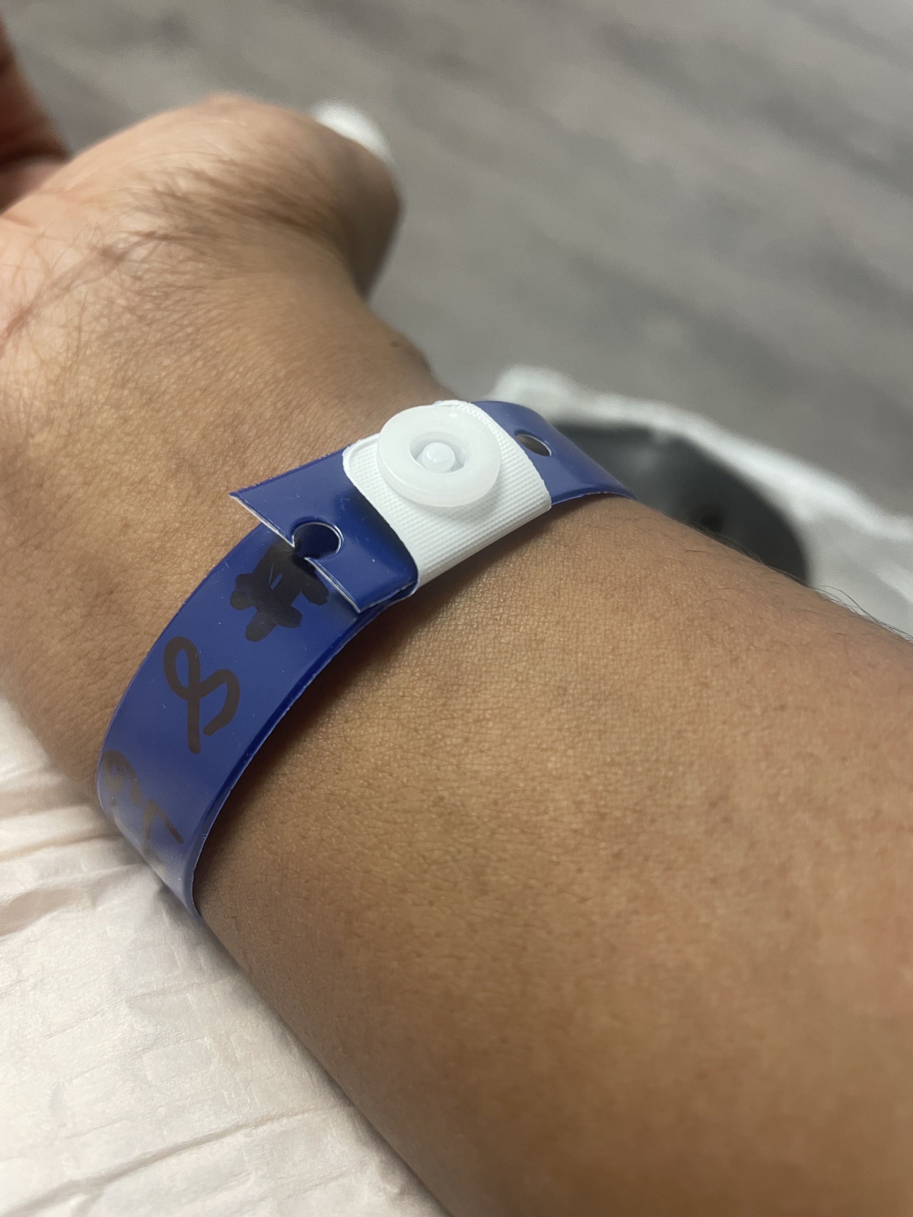 A royal blue medical bracelet on Jordan&#x27;s wrist. &quot;#8&quot; is written on the bracelet in black marker