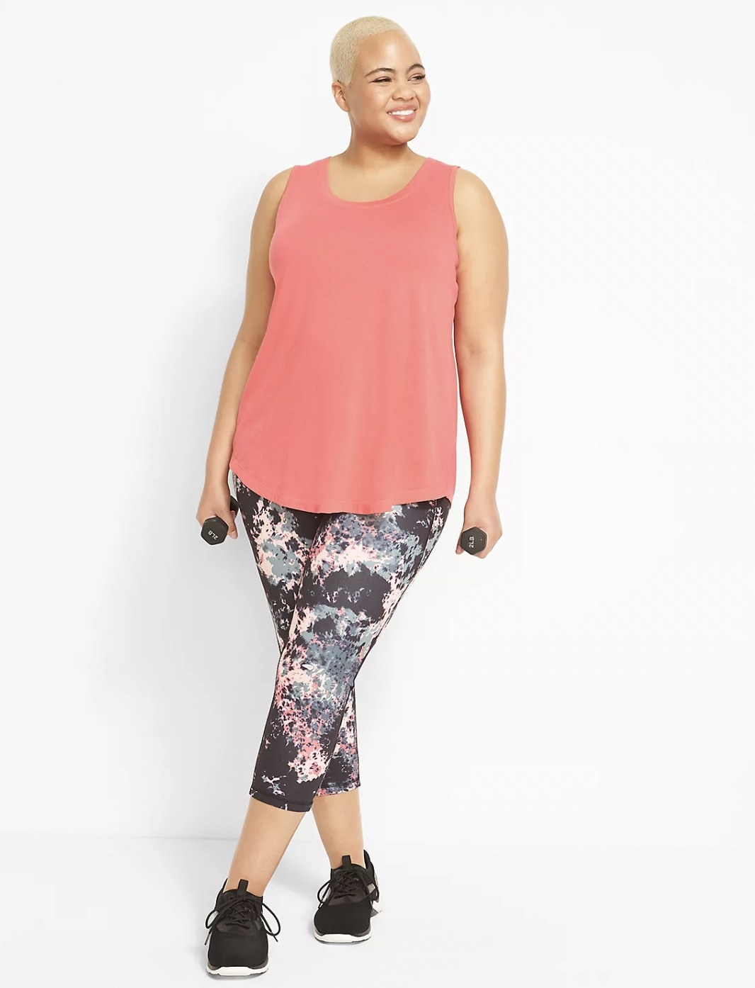 Model in the capri leggings with pink workout tank and holding small dumbbells in each hand