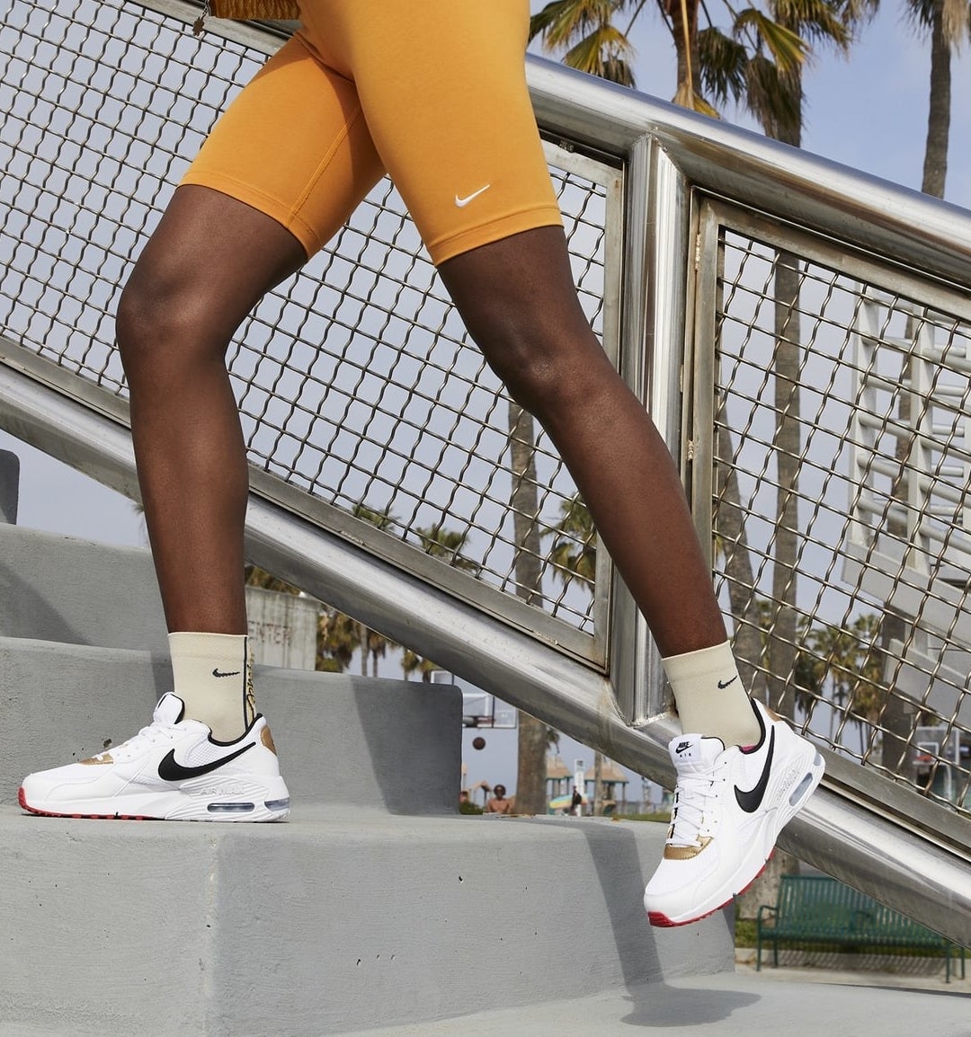 model in white nike shoes and yellow biker shorts