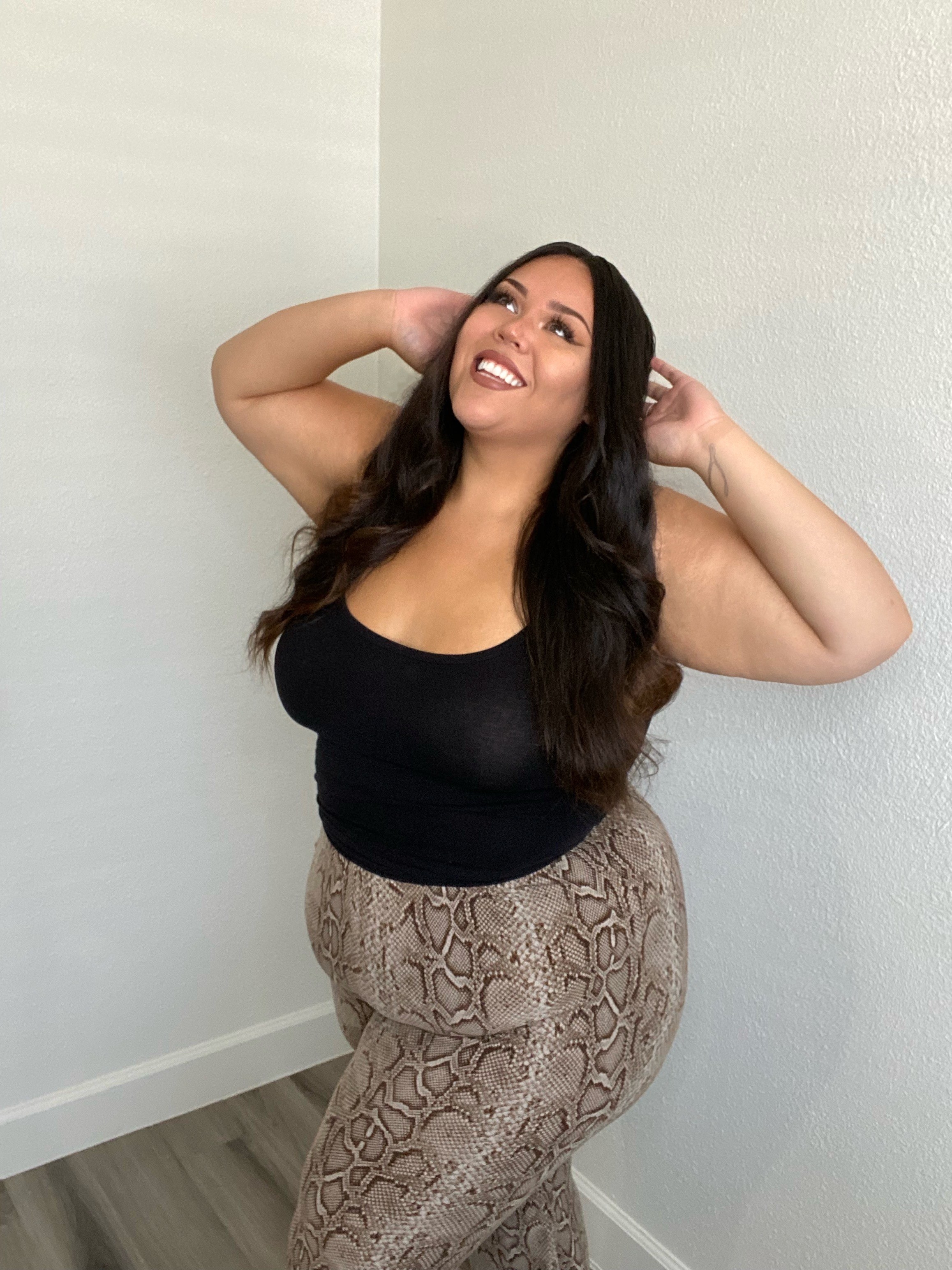 Julia smiles as she is wearing a bodysuit and leggings poses in a room