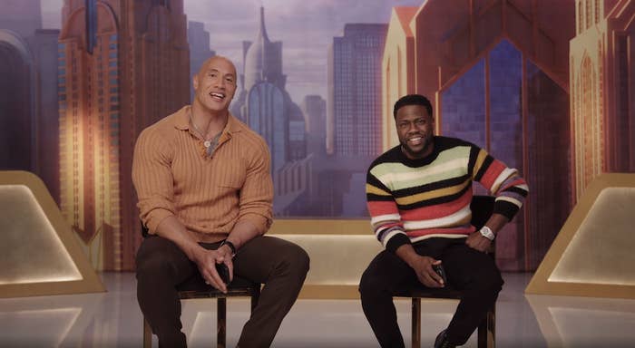 Dwayne and Kevin sit on stools next to each other with a backdrop of skyscrapers behind them
