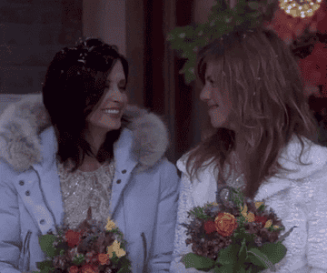 Courteney Cox as Monica and Jennifer Aniston as Rachel smile at each other during Phoebe&#x27;s wedding