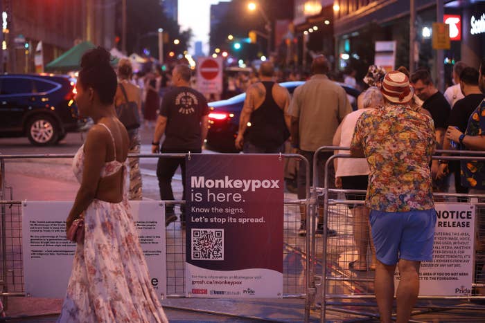In a street festival in Toronto, a poster saying &quot;Monkeypox is here. Know the signs. Let&#x27;s stop its spread&quot; hangs on a crowd control fence.
