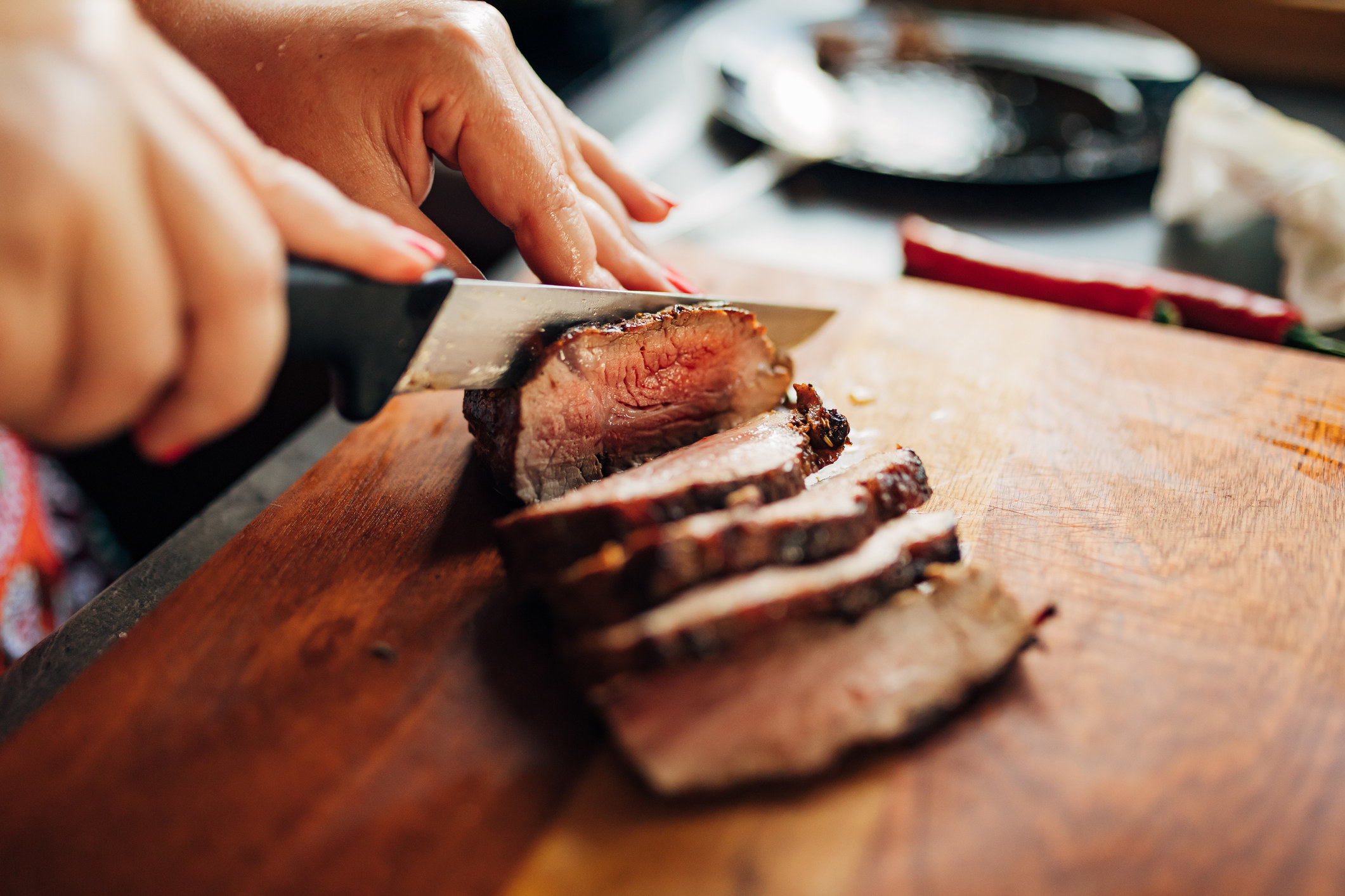 A person slicing a steak on a cutting board.