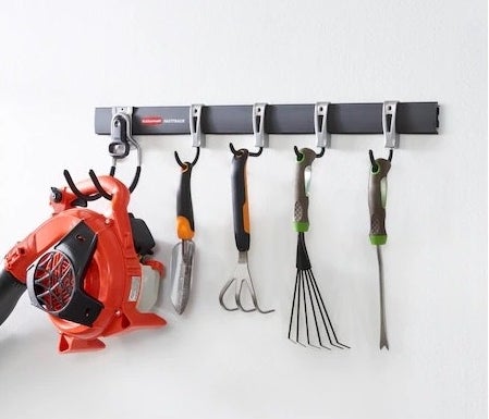 a storage rail system holding a leaf-blower and gardening tools