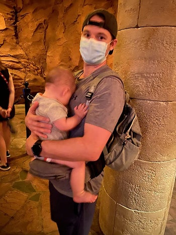 reviewer holding their child in the hip seat carrier at Disney