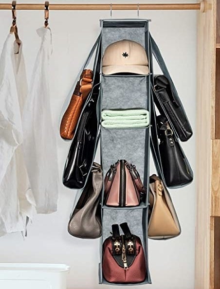The bag organizer hanging up in a closet with bags in all of the cubby holes