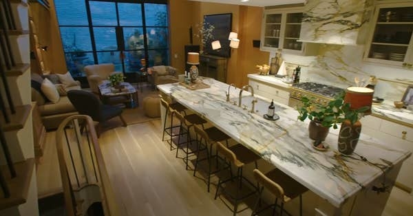 Nate and Jeremiah&#x27;s kitchen at their New York home, including countertops with gold and black veining and light ochre walls