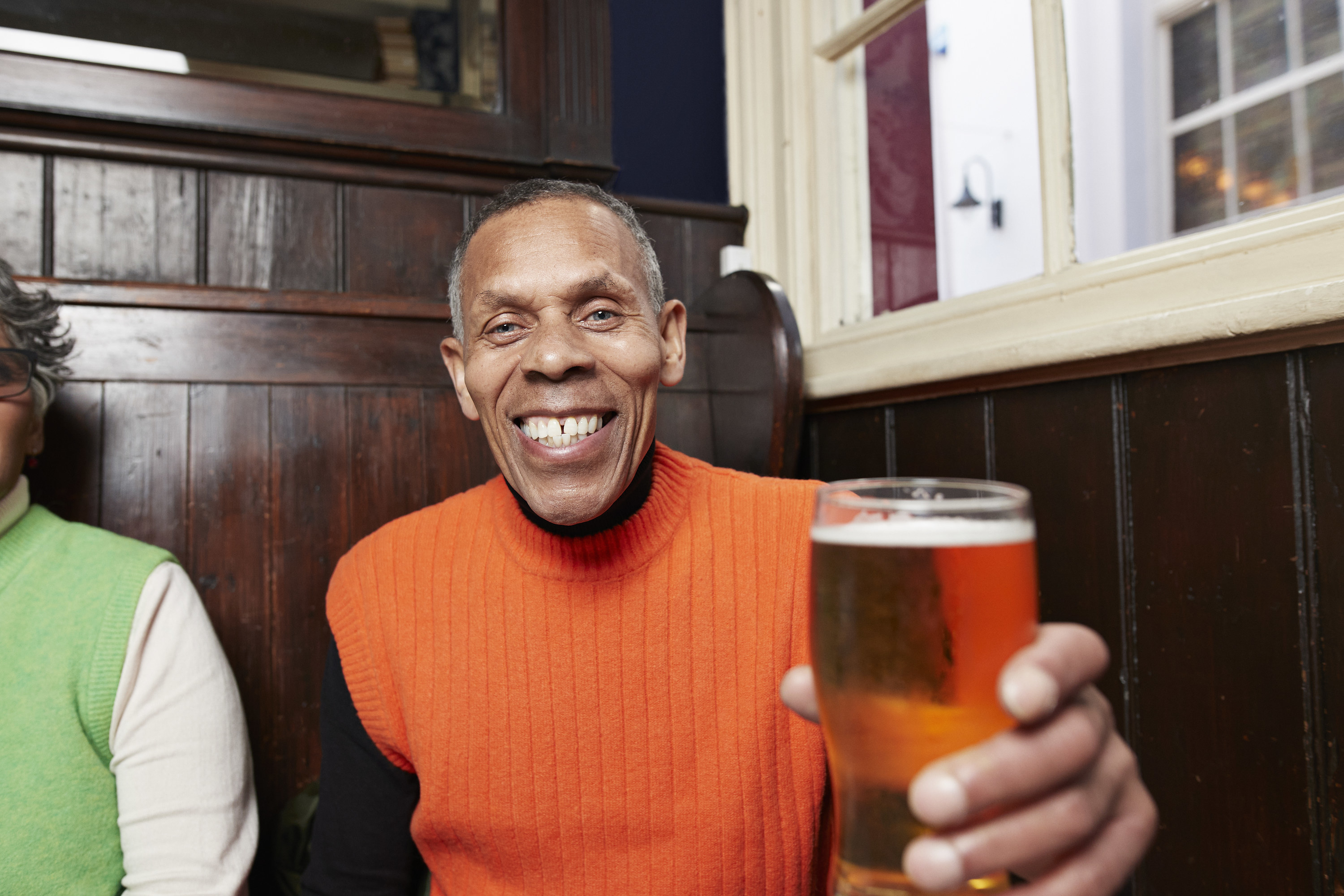 Smiling man sitting in a pub and holding a glass of beer