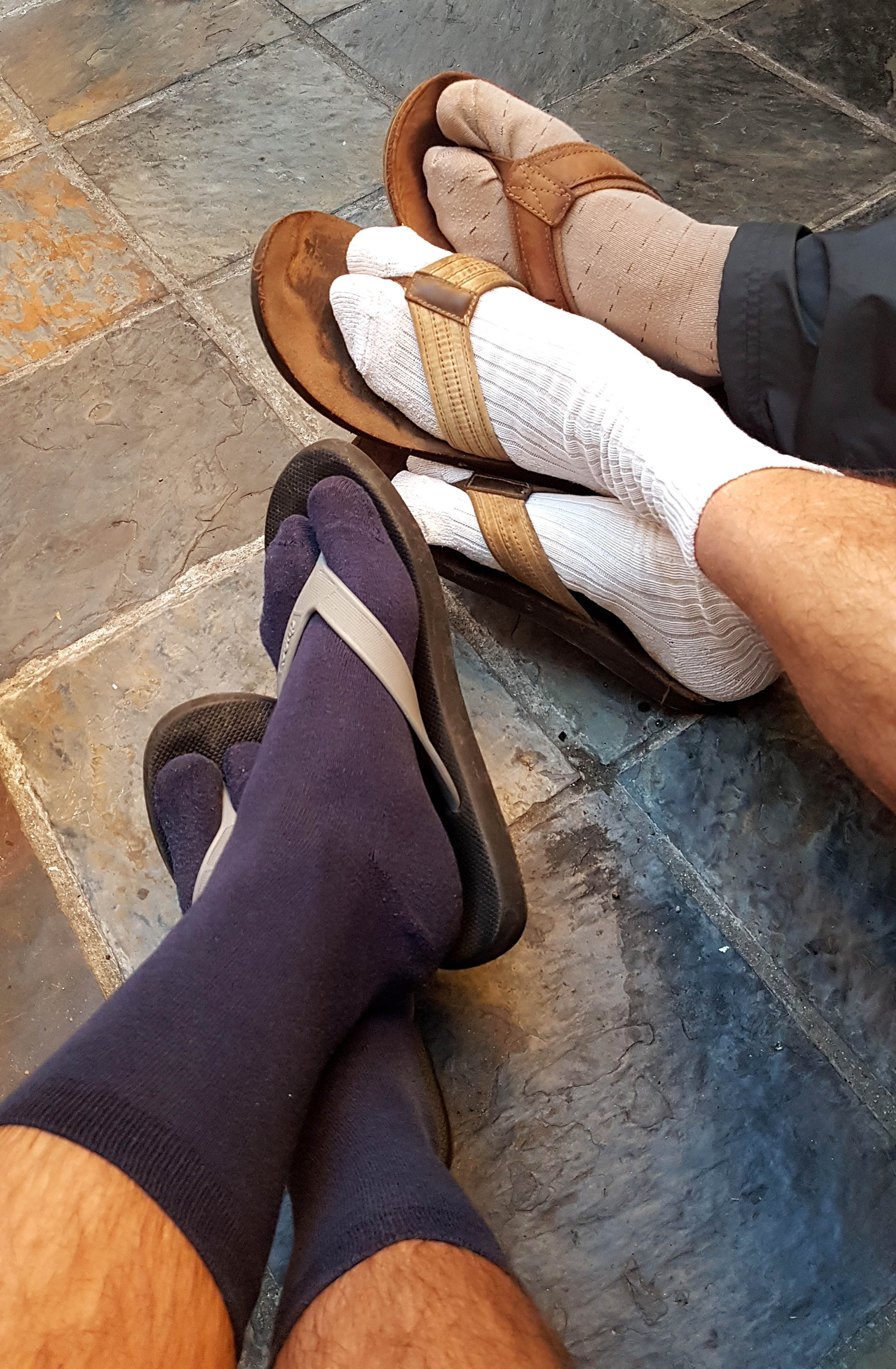Three pairs of feet wearing socks and sandals
