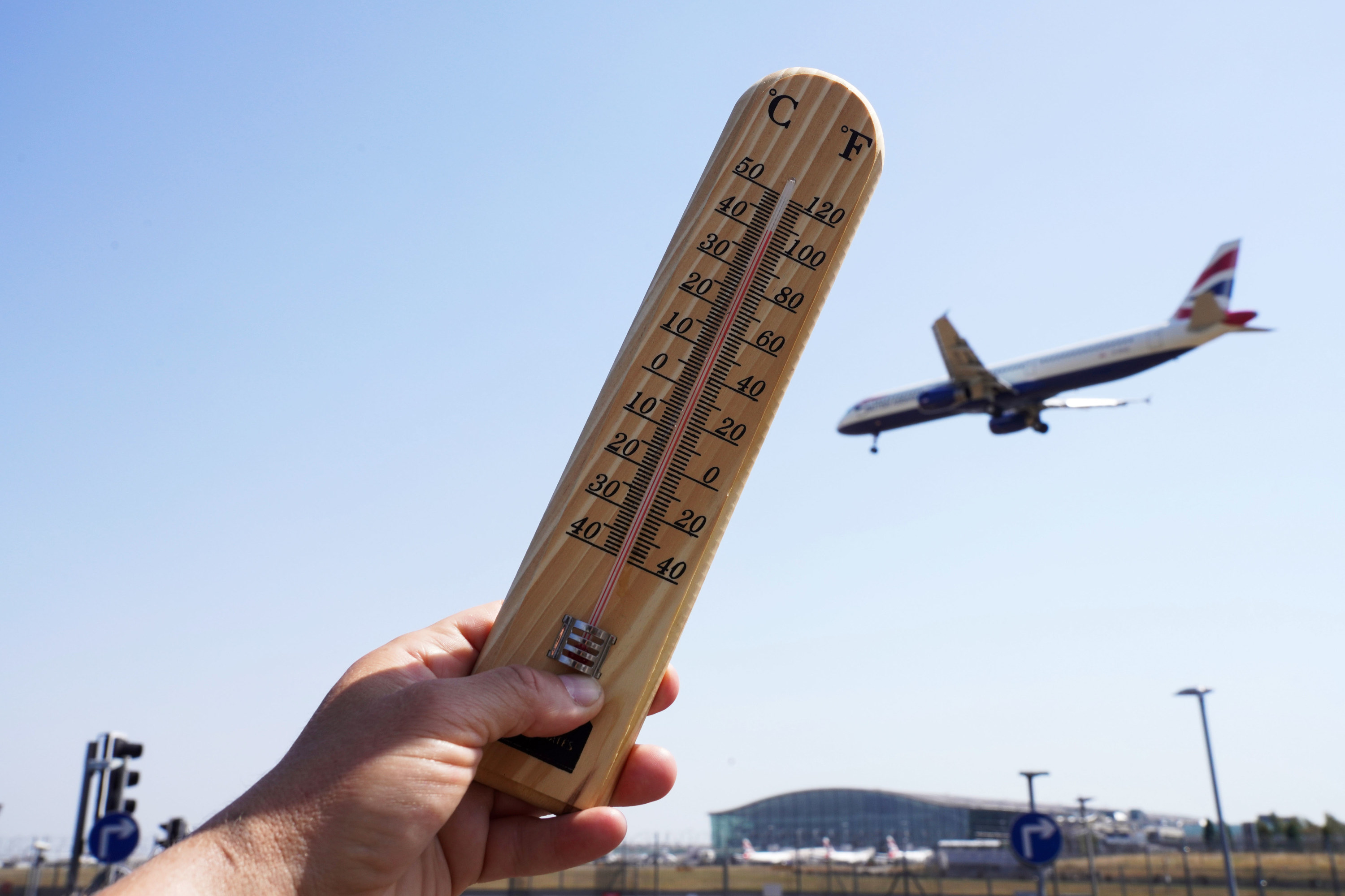 Someone holds a thermometer outside that reads over 100 degrees Fahrenheit